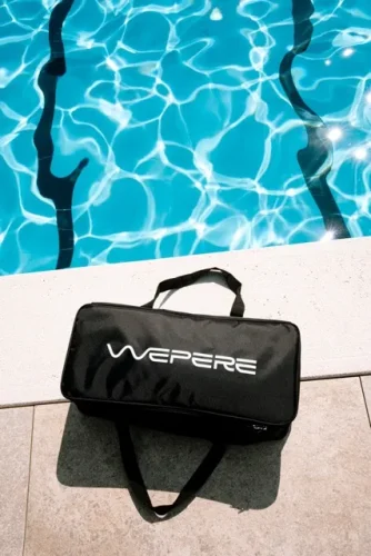 Borsa nera da trasporto Wepere posizionata sul bordo di una piscina con acqua azzurra e riflessi di luce.