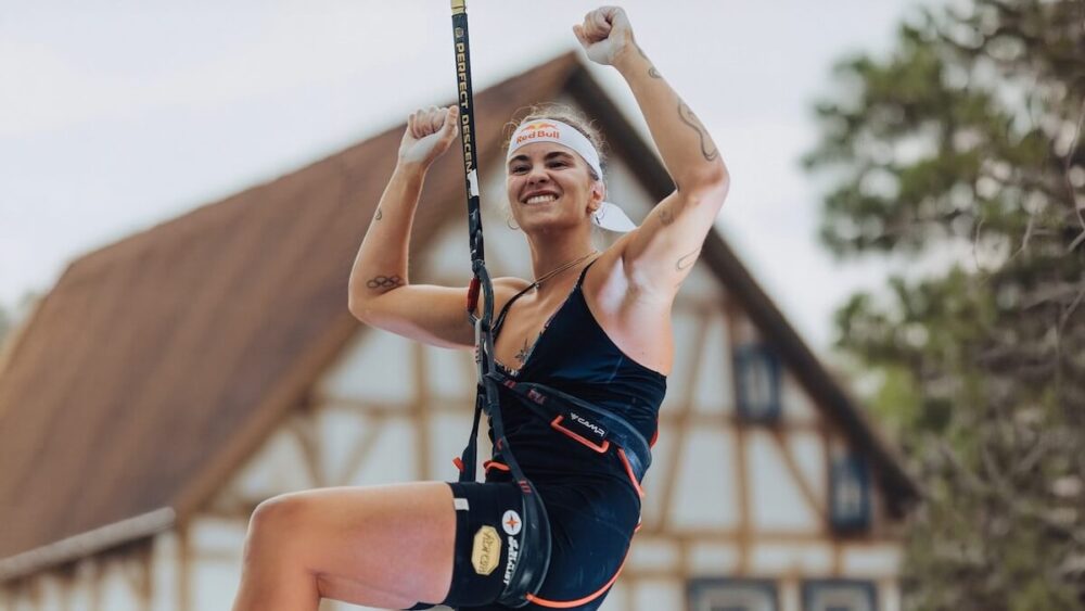 Beatrice Colli sorride durante una sessione di arrampicata sportiva speed con imbrago di sicurezza, ottimizzando la forza con WEPERE